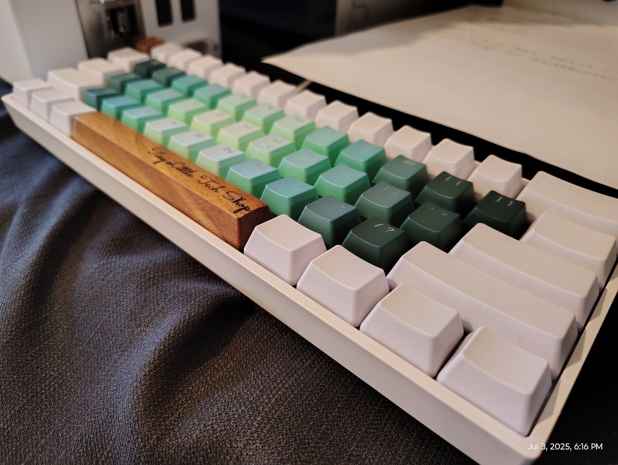 White mechanical keyboard with green gradient keycaps and a wood spacebar